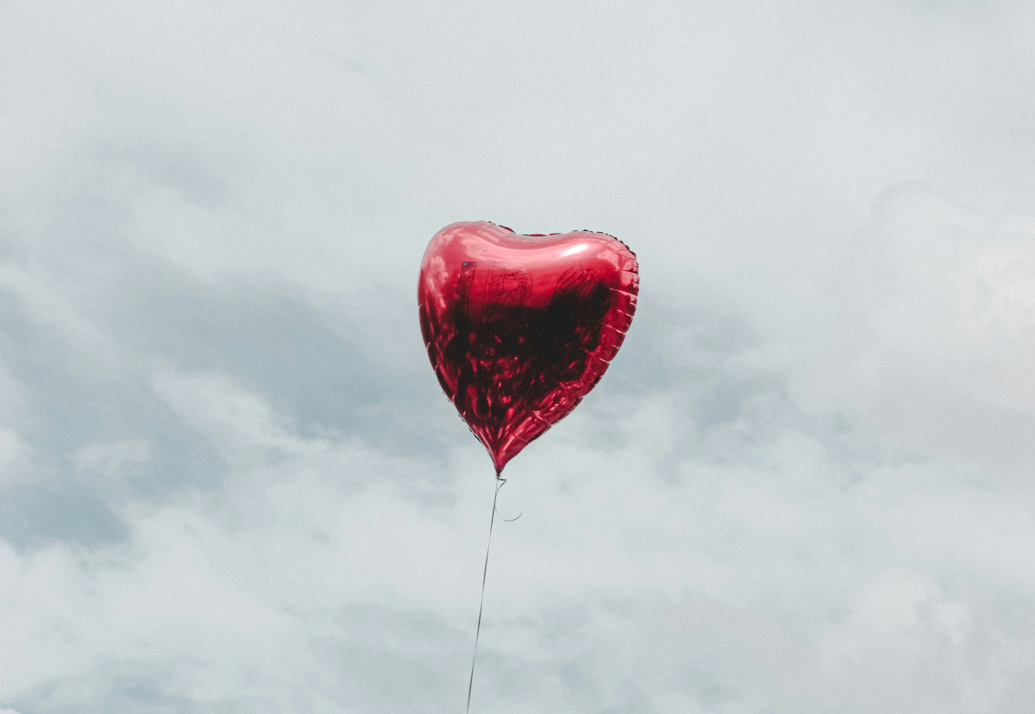 Heart-shaped balloon floating in a cloudy sky